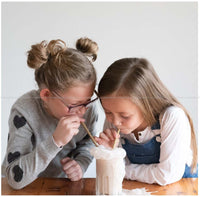 two female kids sharing a shake drink using two Wooden Bamboo Straws